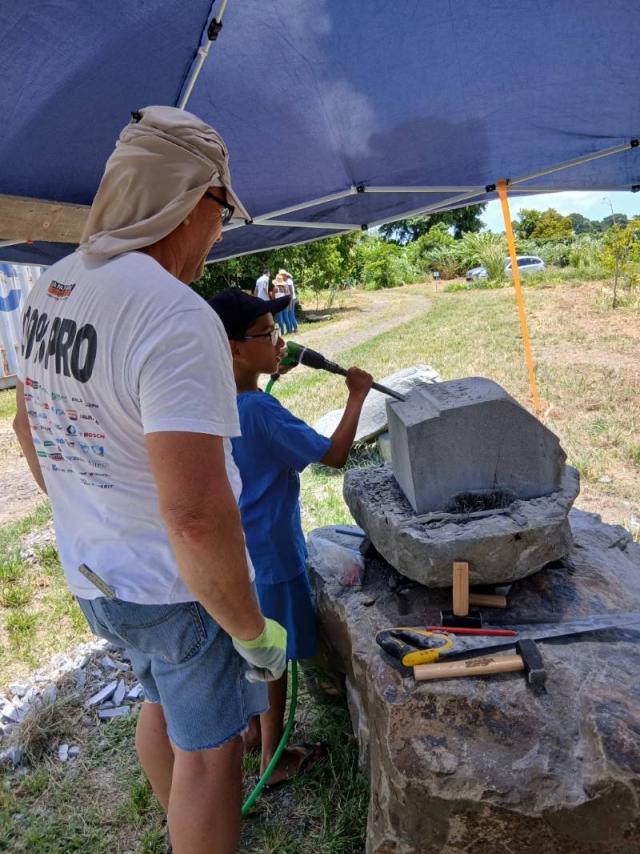 Ce samedi 19 juillet 2025, le site archéologique de Vivé, au Lorrain, a accueilli plus d’une soixantaine de visiteurs venus vivre une expérience unique autour des pétroglyphes amérindiens, en présence de Patrick Grob, maître tailleur de pierre de renommée internationale.  Organisée par CAP Nord Martinique, cette journée portes ouvertes a plongé les participants dans l’univers de la vie précolombienne, à travers  une présentation des futures grandes étapes d’aménagement du Parc Caribéen de la Vie Amérindienne. L’intervention très attendue de Patrick Grob, artisan ornementiste et Compagnon du Devoir, a captivé petits et grands. Il a partagé son savoir-faire et sa passion pour la pierre, avant d’inviter les participants à s’initier eux-mêmes à la taille, dans une ambiance conviviale et pédagogique. Hormis la taille de pierre, d’autres ateliers interactifs ont animé la journée : Dessin sur galet, Chasse aux trésors ou encore Initiation au tir à l’arc. Parents et enfants ont apprécié les animations et le plaisir de partager un moment ludique en pleine nature, au cœur d’un site patrimonial majeur du Nord. Les retours enthousiastes des visiteurs témoignent de l’intérêt croissant pour ce projet porté par CAP Nord Martinique. Tous sont repartis curieux, enrichis et impatients de découvrir l’ouverture prochaine du parc de Vivé.